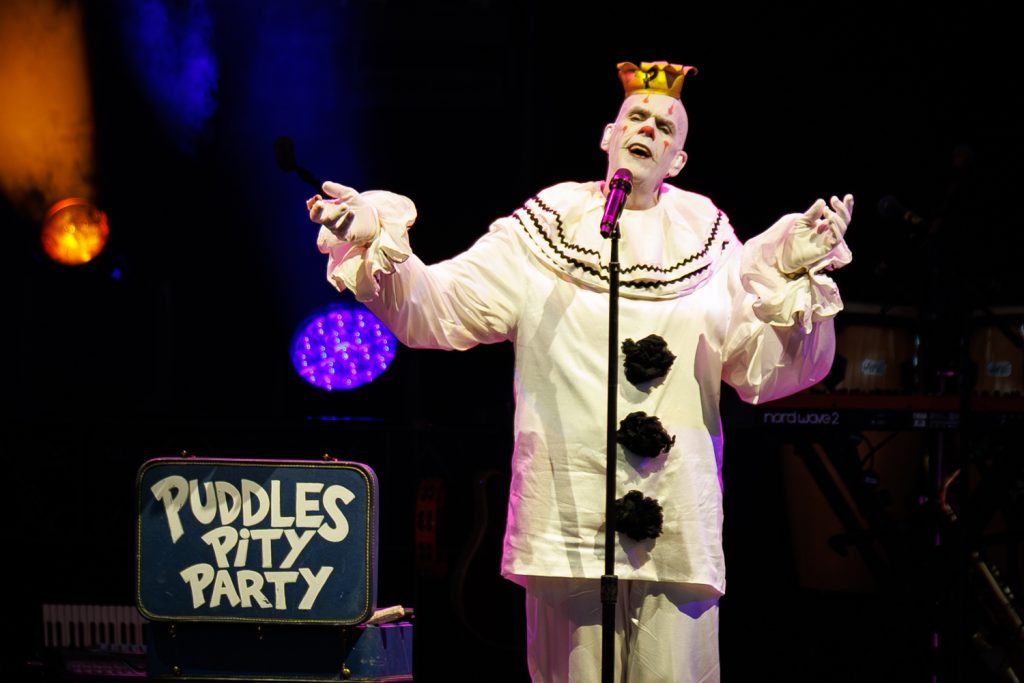 Clown performing on stage with microphone.
