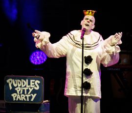 Clown performing on stage with microphone.